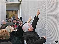 Visitors point to names engraved on the 